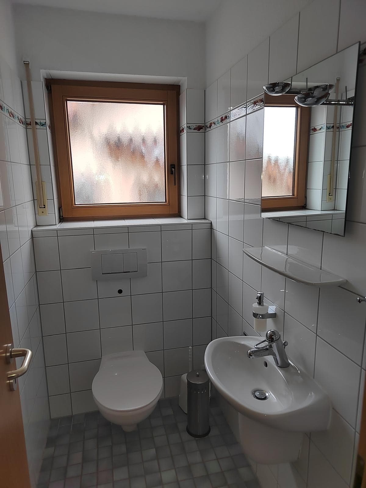 Gäste-WC mit Waschbecken, WC, weißen Fliesen und Milchglasfenster