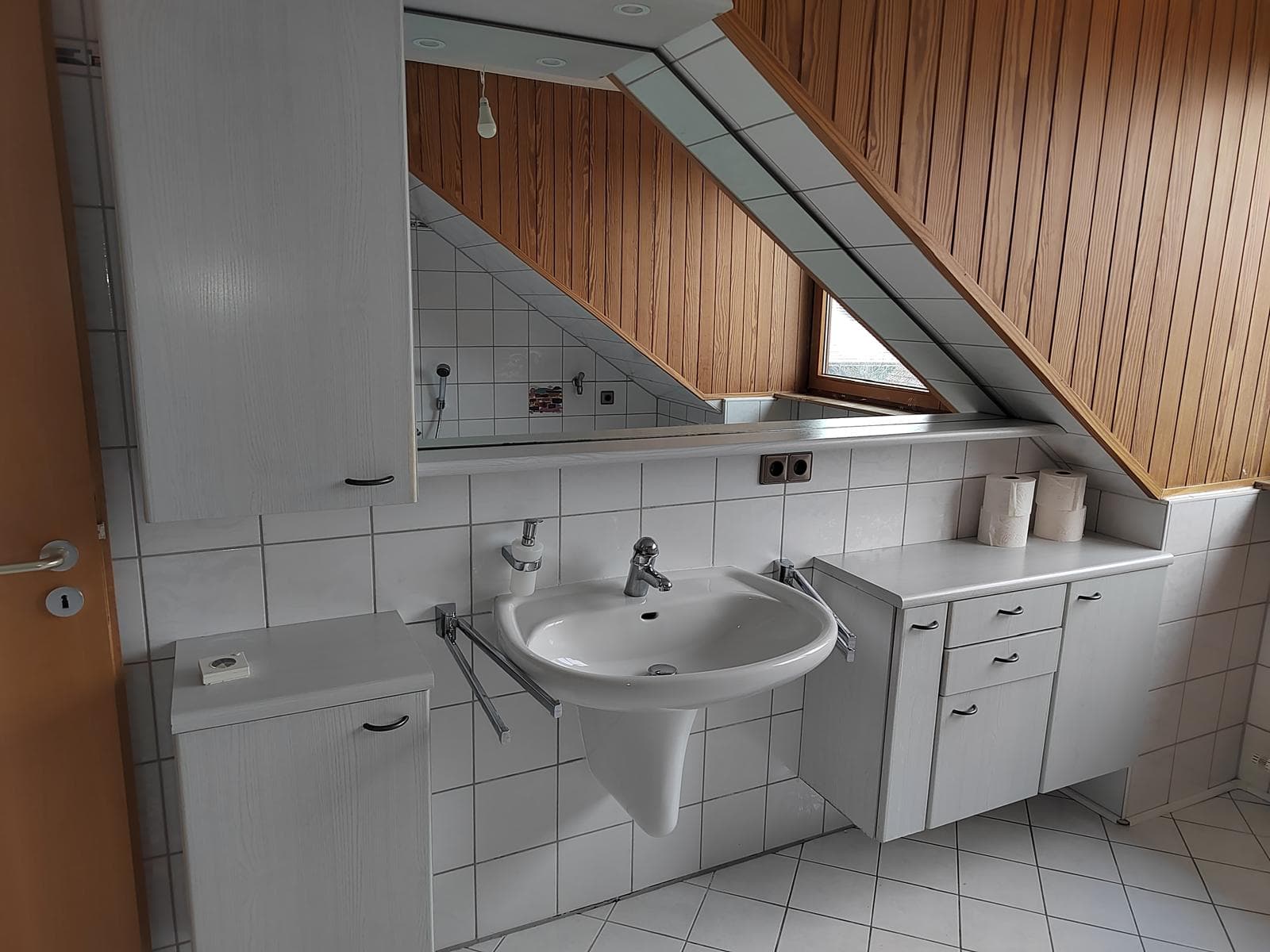 Bad mit Waschbecken, Spiegelschrank, Holzdecke und Dachfenster